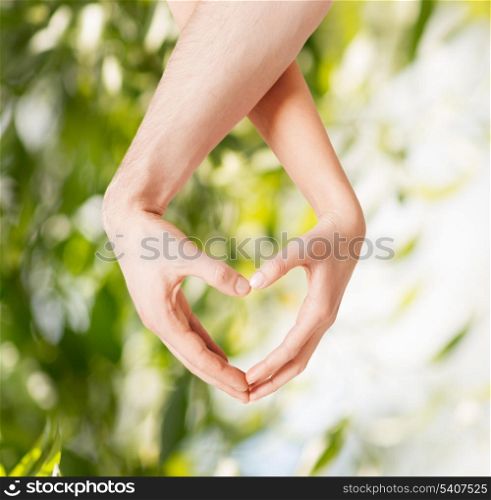 eco, bio, nature, love, harmony concept - woman and man hands showing heart shape