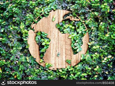 Eco concept :Wood texture world icon on green leaves wall.