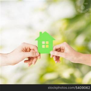 eco, family and real estate concept - closeup picture of woman and man hands holding green house
