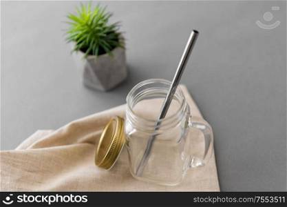 eco friendly concept - empty glass mug of with reusable metallic straw. empty glass mug of with reusable metallic straw