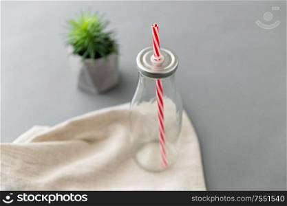 eco friendly concept - empty reusable glass bottle of with striped straw. empty reusable glass bottle of with striped straw