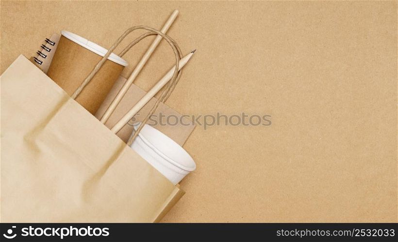 Eco friendly concept, notebook pencil and paper cup with straws in paper bag on wooden background.