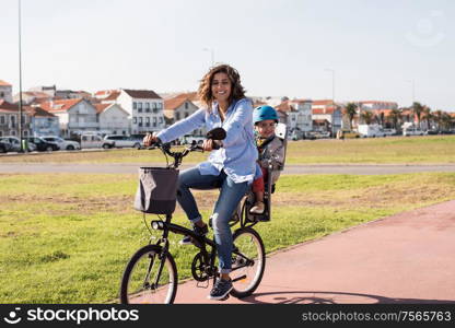 Eco-friendly Family. Mother riding on a bicycle with young kid