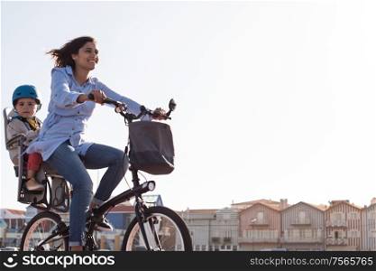 Eco-friendly Family. Mother riding on a bicycle with young kid