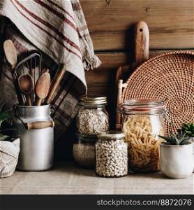 Eco-friendly kitchen concept  Kitchen cooking utensils, house plants and cooking ingredients in glass jars against rustic kitchen wall, front view. Eco-friendly kitchen concept  Kitchen cooking utensils, house plants and cooking ingredients in glass jars against rustic kitchen wall