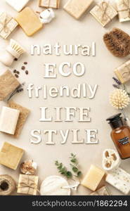 Eco friendly natural cleaning tools and products with wooden letters - bamboo and coconut dish brushes, luffa loofah sponge, baking soda and handmade soap bars on beige background. Zero waste concept. Plastic free life. Flat lay, top view