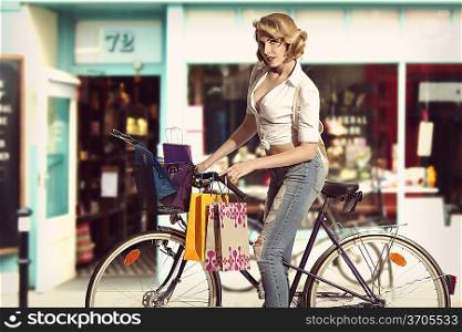 Eco-friendly shopping girl on bicycle with some bags in summer time. She wearing sexy shirt and jeans in vintage color