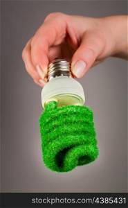 Eco light bulb in hand on gray background