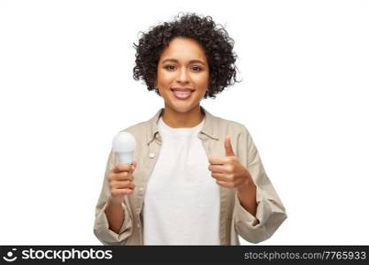 eco living, energy saving and sustainability concept - portrait of happy smiling woman holding lighting bulb over white background. happy smiling woman holding lighting bulb