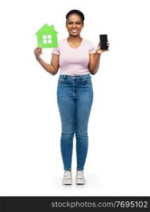 eco living, environment and sustainability concept - happy smiling young african american woman holding smartphone and green house over white background. african woman with smartphone and green house