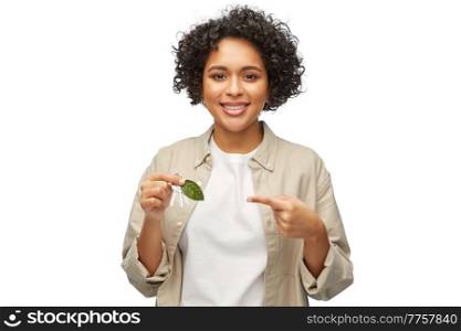 eco living, environment and sustainability concept - portrait of happy smiling woman holding house keys with green leaf over white background. woman holding house keys with green leaf