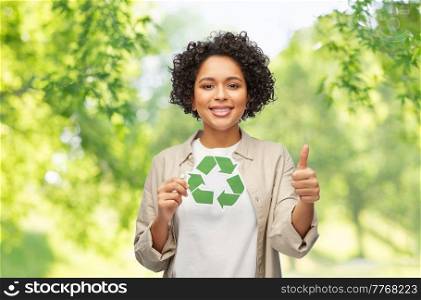 eco living, environment and sustainability concept - portrait of happy smiling woman holding green recycling sign over natural background. happy woman holding green recycling sign