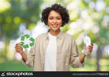 eco living, environment and sustainability concept - portrait of happy smiling woman holding green recycling sign and plastic bottle over green natural background. woman with green recycling sign and plastic bottle