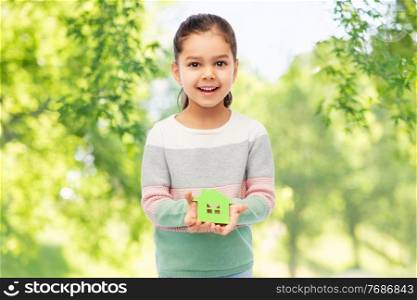eco living, environment and sustainability concept - smiling little girl holding green house icon over green natural background. smiling little girl holding green house icon
