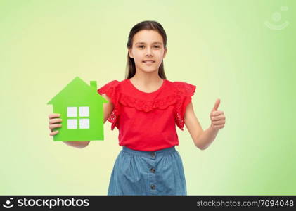 eco living, environment and sustainability concept - smiling little girl holding green house icon showing thumbs up over natural background. happy girl with green house icon showing thumbs up