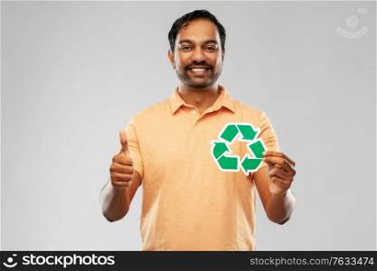 eco living, environment and sustainability concept - smiling young indian man in polo t-shirt holding green recycling sign over grey background. smiling indian man holding green recycling sign