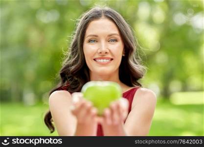 eco living, healthy eating and people concept - portrait of happy woman with green apple at summer park. happy woman eating green apple at summer park