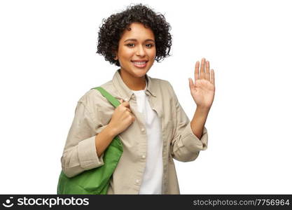 eco living, zero waste and sustainability concept - portrait of happy smiling woman with green reusable canvas bag for food shopping waving hand over white background. woman with reusable canvas bag for food shopping