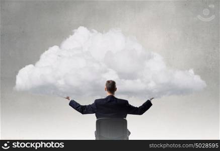 Eco or cloud computing. Back view of businessman in chair holding white cloud