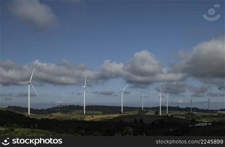 Eco power, landscape with hills and wind turbine field on blue sky background.