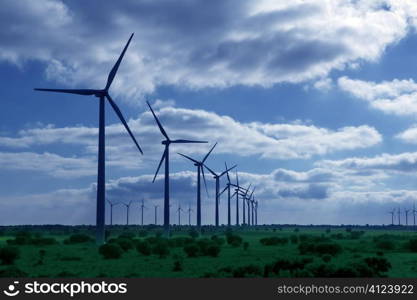 Ecological elecric energy production by windmills in a meadow and blue sky