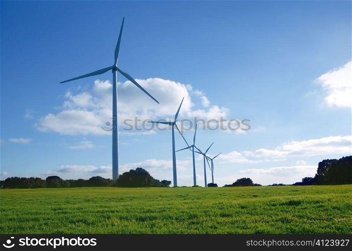 Ecological elecric energy production by windmills in a meadow and blue sky