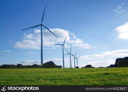 Ecological elecric energy production by windmills in a meadow and blue sky