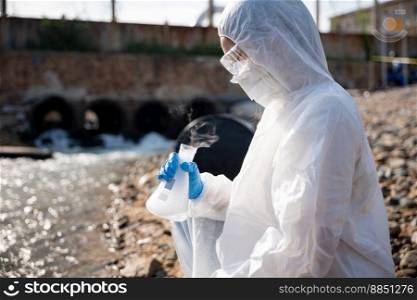 Ecologist s&ling water toxic chemicals from river with test tube glass and have white smoke, Biologist wear protective suit and mask collects s&le waste water from industrial, problem environment
