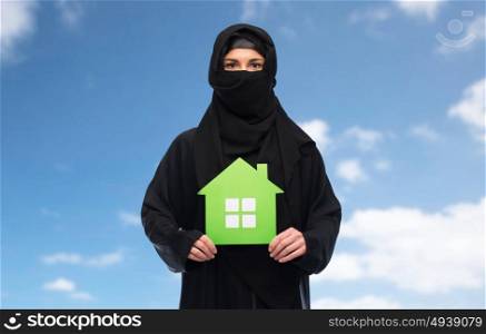 ecology and people concept - muslim woman in hijab with green house over blue sky and clouds background. muslim woman in hijab with green house over white