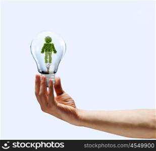 Ecology concept. Human hand holding bulb with plant shaped like man