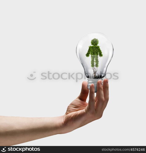 Ecology concept. Human hand holding bulb with plant shaped like man