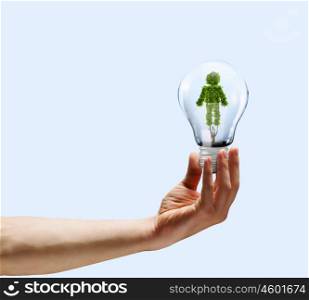 Ecology concept. Human hand holding bulb with plant shaped like man