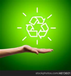 Ecology concept. Recycling symbol in human hand against green background