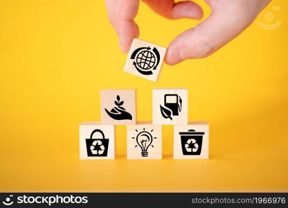 Ecology concept with icons on wooden cubes, yellow background. The concept of clean energy for the whole world.. Ecology concept with icons on wooden cubes, yellow background.