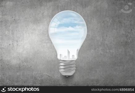 Ecology concept with light bulb and city inside. Electric green energy