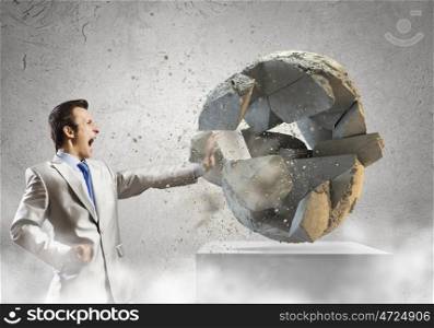 Ecology concept. Young determined businessman crashing Earth planet with punch. Elements of this image are furnished by NASA