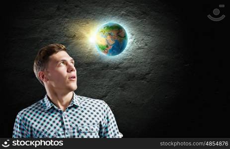 Ecology concept. Young man against dark background and Earth planet image. Elements of this image are furnished by NASA