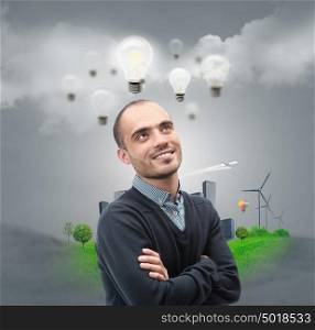 Ecology ideas concept. Businessman standing in front of cityscape with lamp overhead