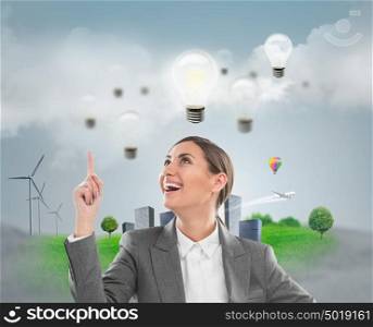Ecology ideas concept. Businesswoman standing in front of cityscape with lamp overhead