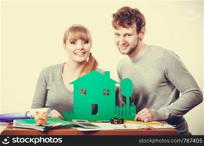 Ecology in practical domestic life. People real estate and house concept. Young couple with green ecological paper house happily thinking of future.. Young couple with ecological green house.