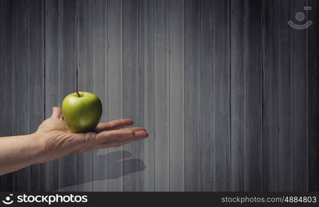 Ecology problem. Close up of hand holding green apple