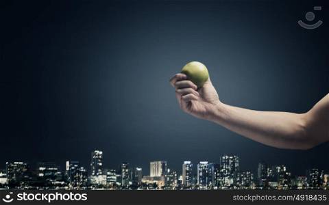 Ecology problem. Close up of hand holding green apple