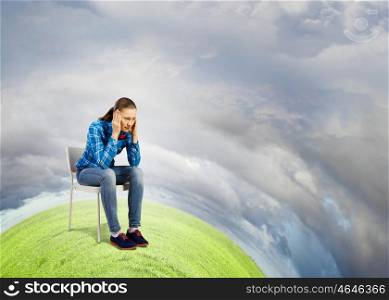 Ecology problem. Young troubled woman sitting in chair on green planet