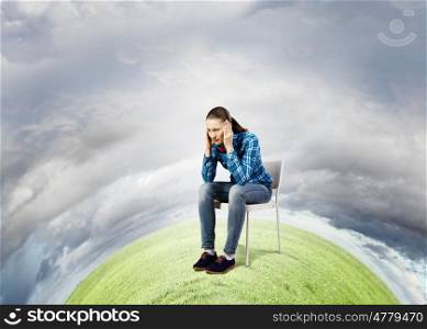 Ecology problem. Young troubled woman sitting in chair on green planet