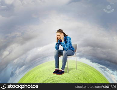 Ecology problem. Young troubled woman sitting in chair on green planet