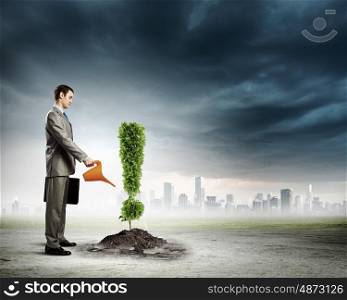 Ecology warning. Image of businessman watering plant shaped like exclamation mark