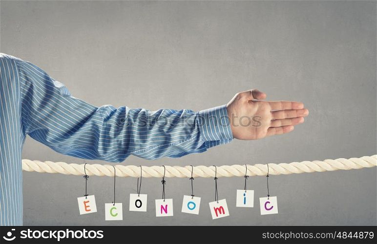 Economics concept. Word economic composed of cards hanging on rope and hand gesture