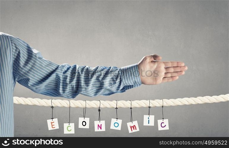Economics concept. Word economic composed of cards hanging on rope and hand gesture