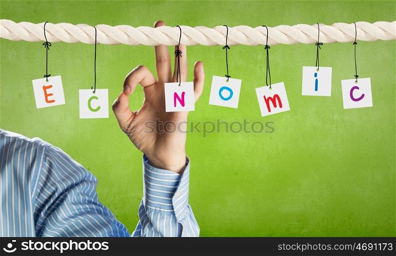 Economics concept. Word economic composed of cards hanging on rope and ok gesture