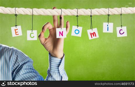 Economics concept. Word economic composed of cards hanging on rope and ok gesture
